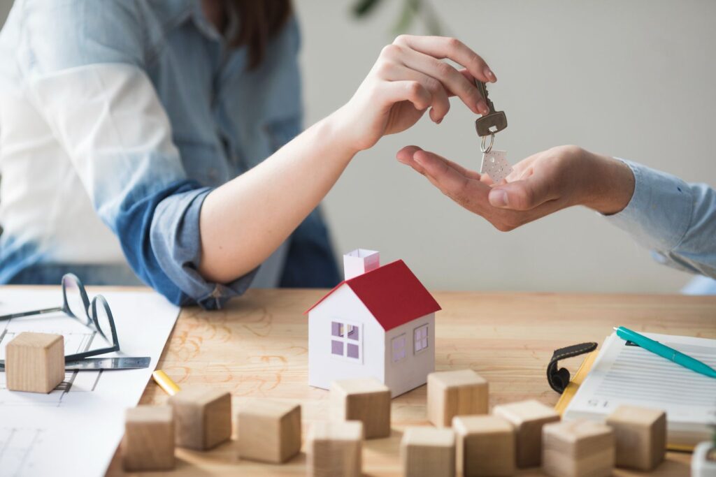 close-up-woman-s-hand-giving-house-key-man-wooden-table (1) (1)
